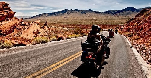 two people riding a motorcycle through mountainess desert