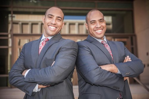Faussette twins standing side by side with arms folded