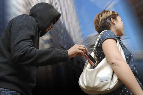 hooded person stealing phone out of womans purse